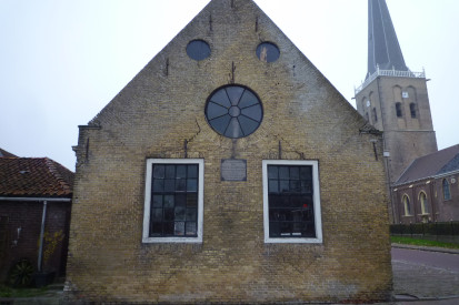 Voormalig schoolgebouw Tzum met op de achtergrond de kerktoren